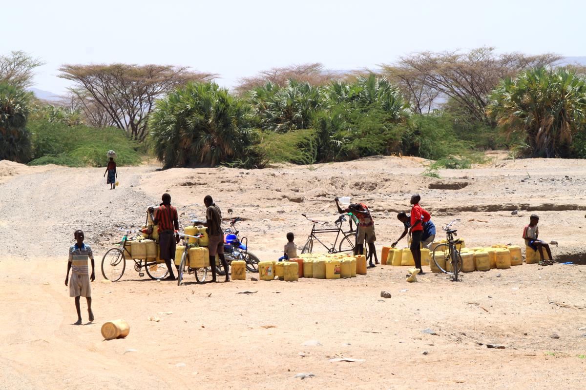 People filling up their water containers at a waterhole. 