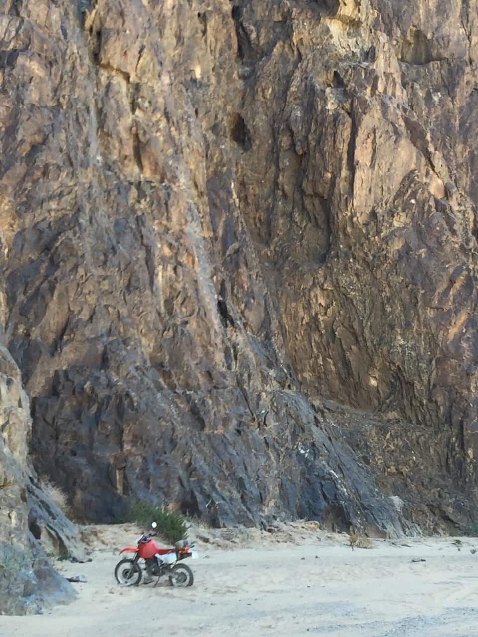 The motorbike is dwarfed by the walls of the Ugab River Canyon. 
